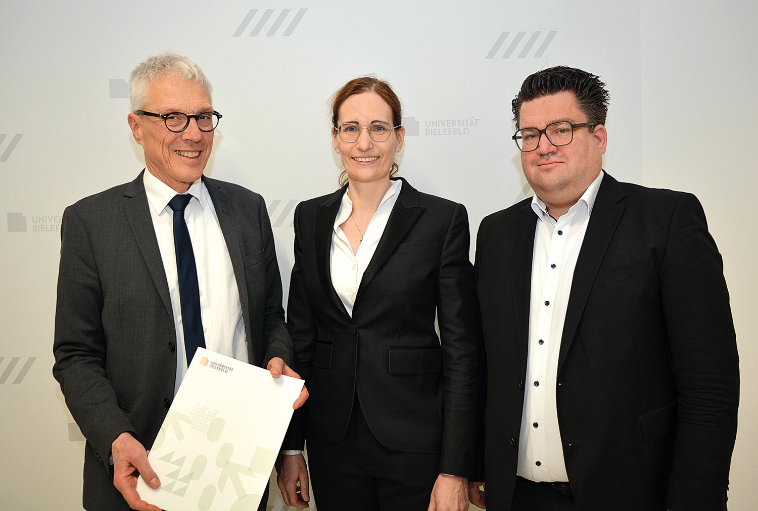 Der Kanzler der Universität Bielefeld Dr. Stephan Becker (l.) übergibt Univ.-Prof. Dr. Claudia Scherl (Mitte) ihre Ernennungsurkunde im Beisein von Bernd Henkemeier, kaufmännischer Direktor des Klinikum Bielefeld (r.). 